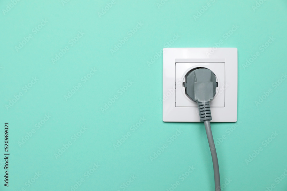 Power socket with inserted plug on turquoise wall, space for text. Electrical supply Power socket with inserted plug on turquoise wall, space for text. Electrical supply