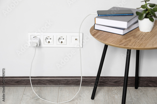 Schilderij op canvas Modern smartphone charging from electric socket indoors