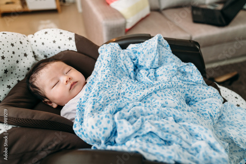 Foto adorable asian new baby covered with blanket is sleeping alone peacefully in the nursery glider during naptime in the living room at home