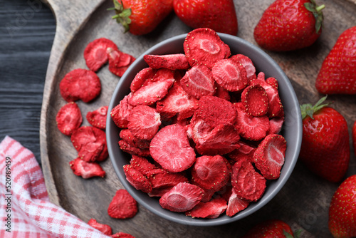 Freeze dried and fresh strawberries on black wooden table, top view photo