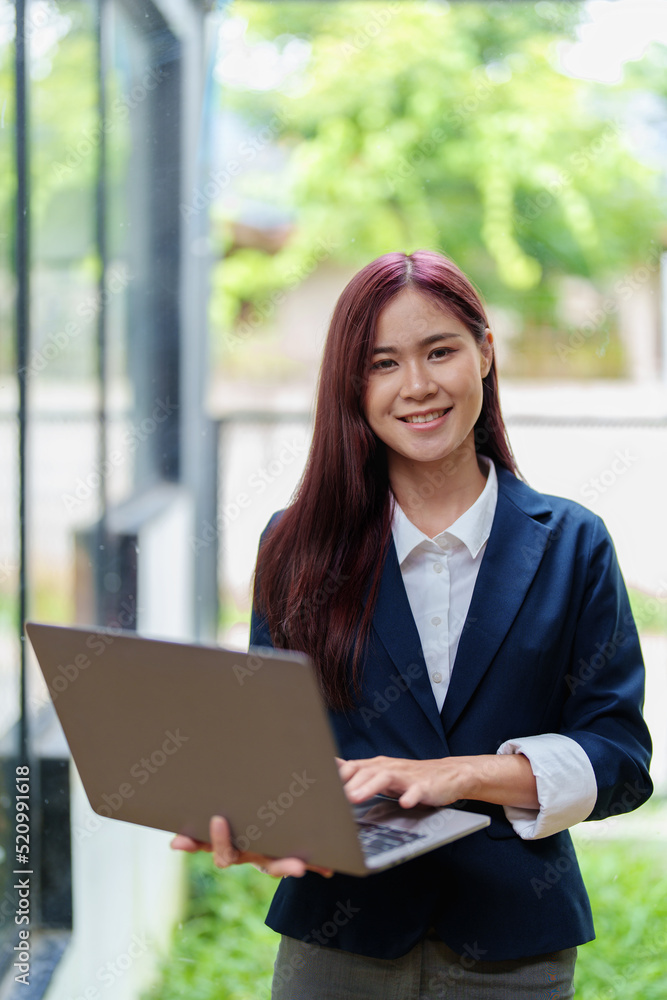 Portrait of a smiling Asian businesswoman holding a computer Portrait of a smiling Asian businesswoman holding a computer