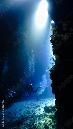 Underwater photo from a scuba dive inside caves and tunnels with rays of light. Beautiful scenery with sunlight and beams underwater in the Red sea in Egypt.