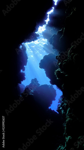Underwater photo from a scuba dive inside caves and tunnels with rays of light. Beautiful scenery with sunlight and beams underwater in the Red sea in Egypt.