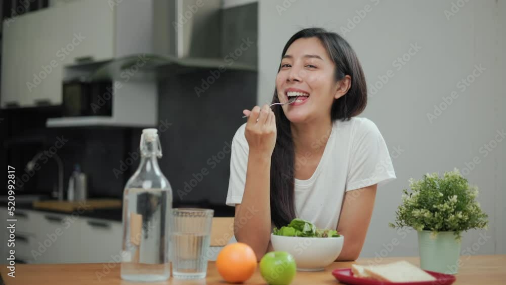 Young female eating organic greens vegetable salad in weight loss diet and wellness on table. Beautiful woman happily eat a healthy salad breakfast in kitchen in the morning. Diet food concept. Young female eating organic greens vegetable salad in weight loss diet and wellness on table. Beautiful woman happily eat a healthy salad breakfast in kitchen in the morning. Diet food concept.