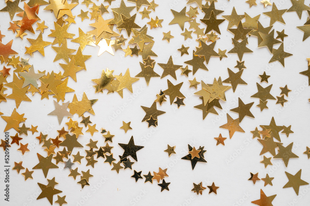 Gold stars shiny glitter on a white background, selective focus Gold stars shiny glitter on a white background, selective focus