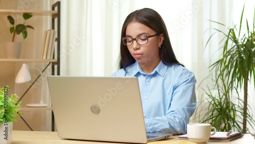 Young black woman in glasses works in the office on a laptop. Girl student is educated remotely using a computer. Manager freelancer at the desktop.