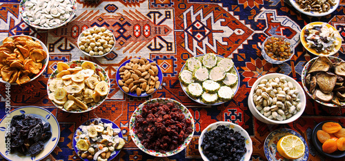 Fototapeta Naklejka Na Ścianę i Meble -  Eastern feast. Asian still life of dried fruits and nuts in plates on a carpet