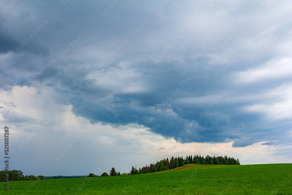 Countryside landscape with green field and forest before thunderstorm Countryside landscape with green field and forest before thunderstorm