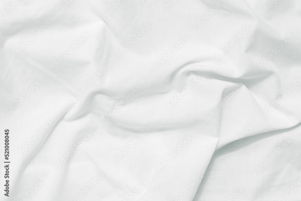 White crumpled bed sheet background, top view. Natural fabric pattern, wrinkle texture. Surface of creases cotton textile. Empty space.