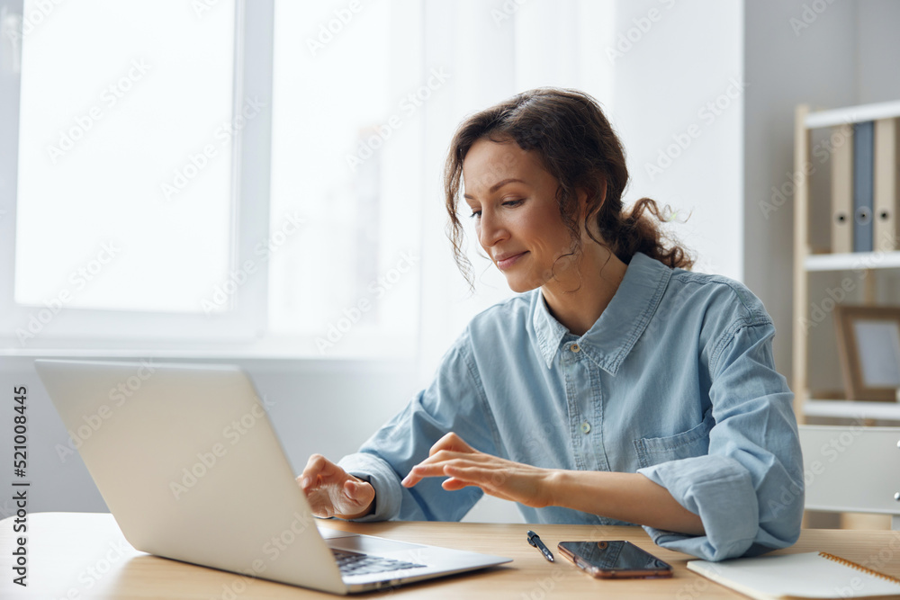 Cheerful adorable curly businesswoman worker freelancer chatting with client registers an order in social media in light office. Happy employee work on computer online in support service. Copy space Cheerful adorable curly businesswoman worker freelancer chatting with client registers an order in social media in light office. Happy employee work on computer online in support service. Copy space