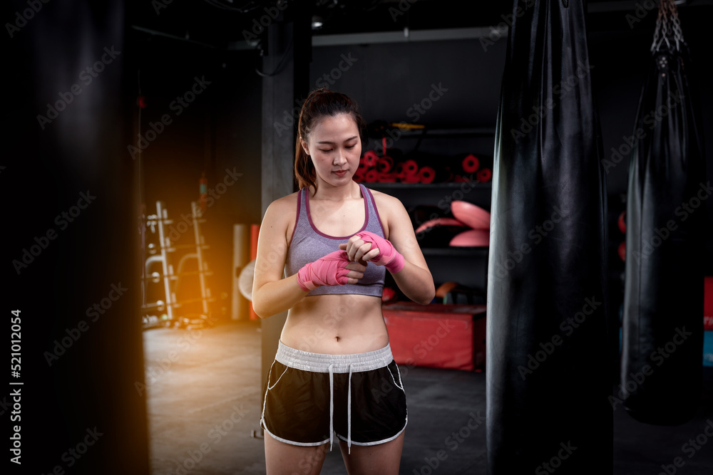 Young fitness woman with sitting on boxing ring .she under wearing boxing bandage safety in boxing exercise .She exercise for strong make muscle and good healthy lifestyle.