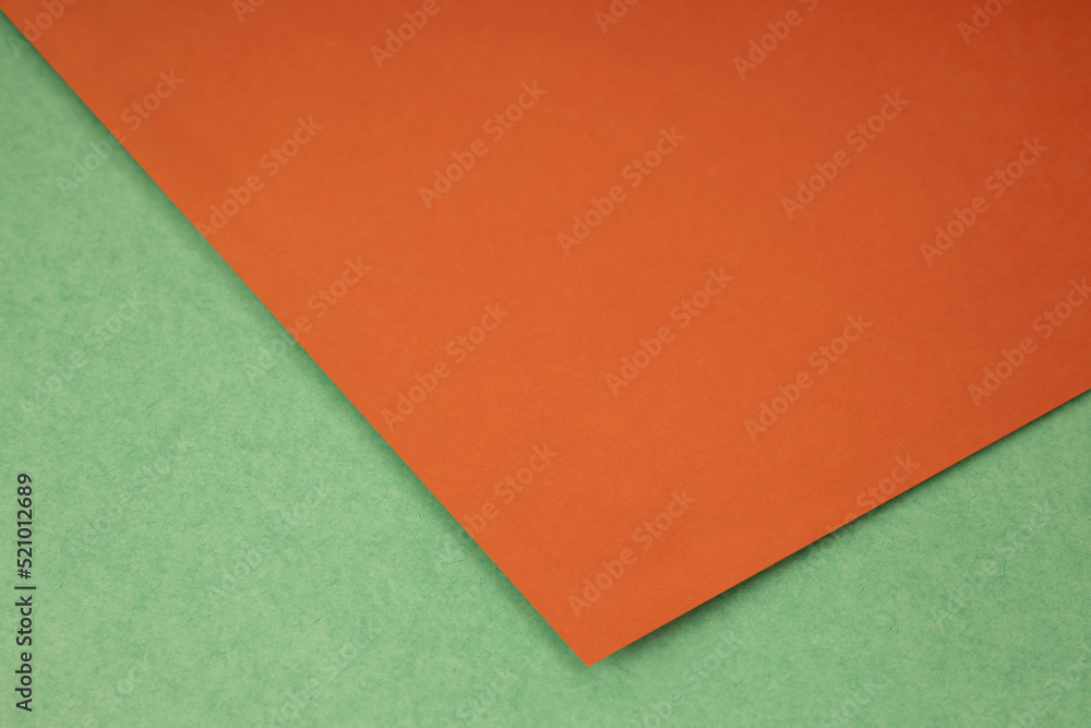 Plain orange paper sheet lying on green textured Background like an open book from top angle Plain orange paper sheet lying on green textured Background like an open book from top angle