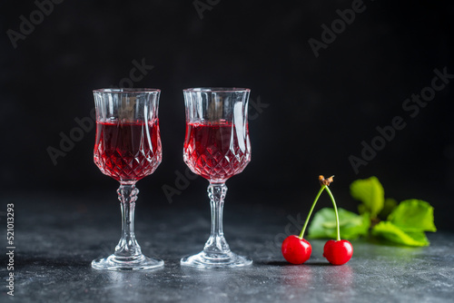 Foto Homemade cherry brandy in two crystal glasses on a black background