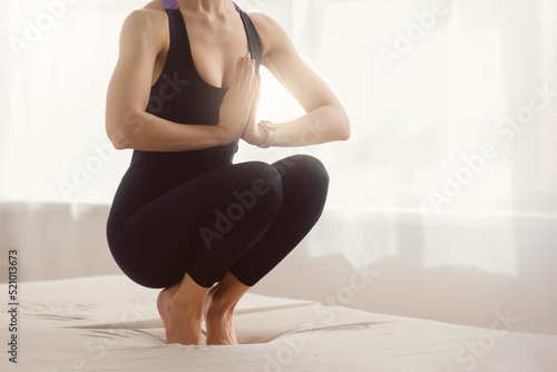 Young healthy relaxed woman in sportswear meditating in light room at home, close up legs