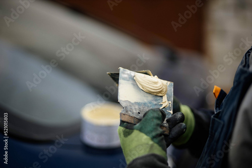 putty on a spatula by a body repair master, puttying a car body. photo