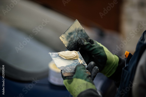 putty on a spatula by a body repair master, puttying a car body. photo