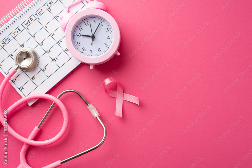 Top view photo of pink ribbon symbol of breast cancer awareness alarm clock calendar and stethoscope on isolated pink background Top view photo of pink ribbon symbol of breast cancer awareness alarm clock calendar and stethoscope on isolated pink background
