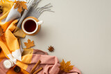 Autumn inspiration concept. Top view photo of cup of tea on rattan serving mat candle cinnamon sticks anise yellow maple leaves pine cones and plaid on isolated grey background with empty space