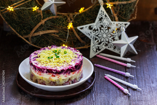 Dressed herring, raditional Soviet festive salad of herring and vegetables in a New Year's decoration.