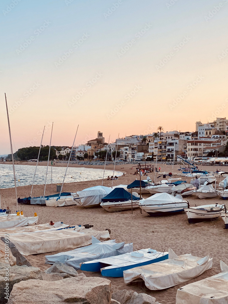 Sant Pol de Mar town on the Maresme coast. Located in the province of Barcelona, ​​Catalonia, Spain. Charming towns in the Mediterranean. Beach with boats on the sand. Sunset hour.