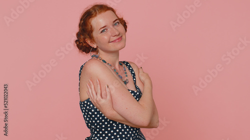 Come to me, I want to embrace you. Young redhead woman in dress spread hands and give hug to you. Pleasant expression, love feelings. Ginger girl with freckles isolated alone on pink studio background