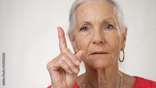 Elderly pretty woman looking to side thinking and then looking into camera coming to resolution.