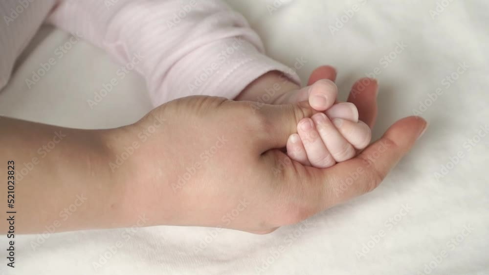 Close up of mothers palms hold little hand of newborn baby. Concept of care and love for child Close up of mothers palms hold little hand of newborn baby. Concept of care and love for child