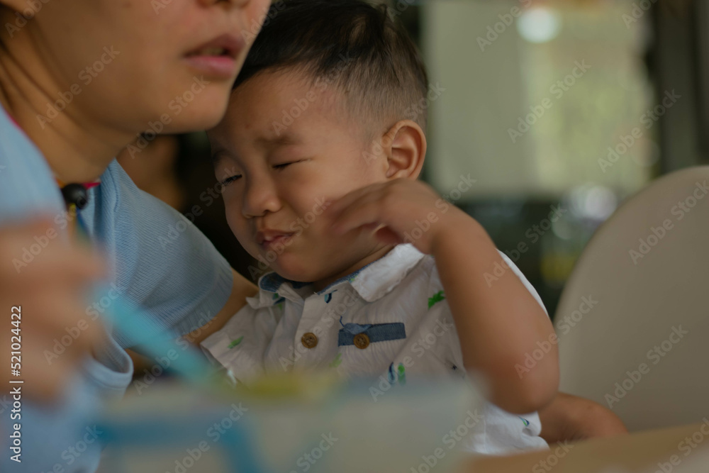 Cute Asian baby boy sitting in a high chair eating rice. Cute Asian baby boy sitting in a high chair eating rice.