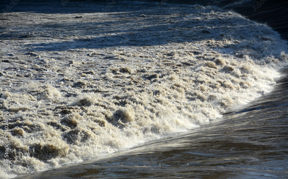 Swirling, churning waters of an earth-rich river that brings floods.