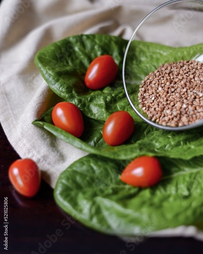 buckwheat in a glass bowl next to tomatoes on lettuce leaves on the table