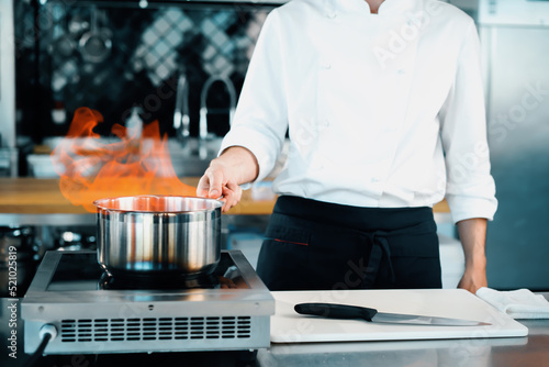 Professional kitchen of the restaurant, close-up: fire from the pot, the process of preparing the sauce