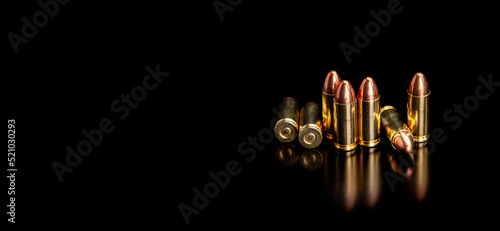 Pistol cartridges 9 mm on a smooth glossy surface with reflections. Ammunition for pistols and PCC carbines on a dark back. photo