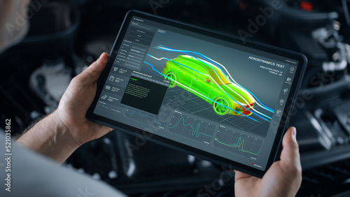 Mechanic engineer holding a digital tablet with engineering research software application on the screen, aerodynamic test of parameters data in the wind tunnel of an eco-friendly car body