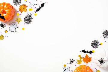 Modern Halloween background with pumpkins, bats, spiders, webs, ghosts, decorations on white table. Halloween party invitation card mockup. Flat lay, top view, copy space.