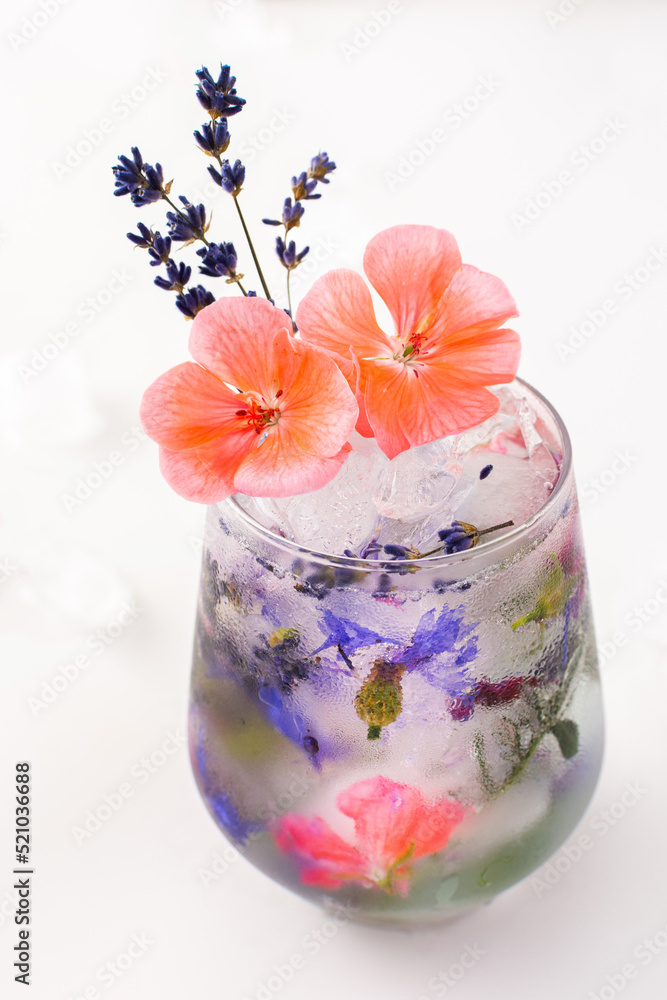 Refreshing cold drink with frozen flowers, cornflowers and geraniums, osteosperum and lavender and carnation