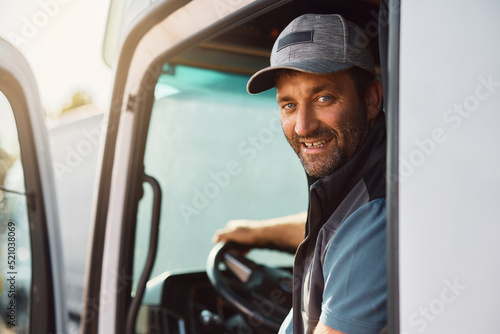 Happy truck driver behind steering wheel looking at camera.