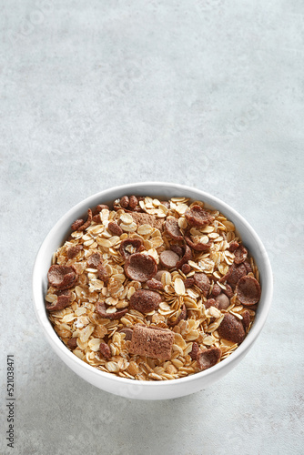 Muesli in a white bowl on a neutral background viewed from above. Copy space