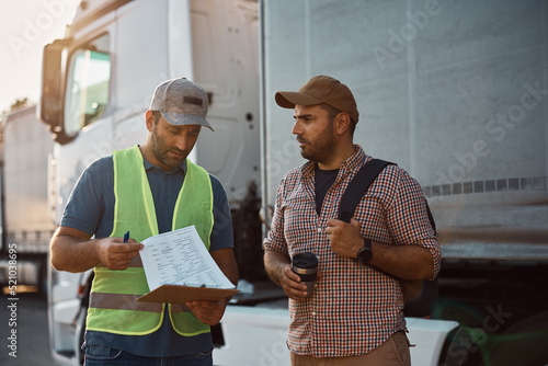 Bild auf Leinwand Truck driver and his dispatcher analyzing shipment list on parking lot