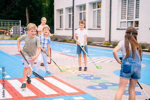 Children playing street hockey on a city holiday on the playground. Happy kids group have fun. Summer activites for children concept. © Iryna
