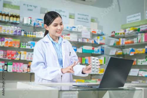 Female pharmacist counseling customer via video call in a modern pharmacy drugstore.