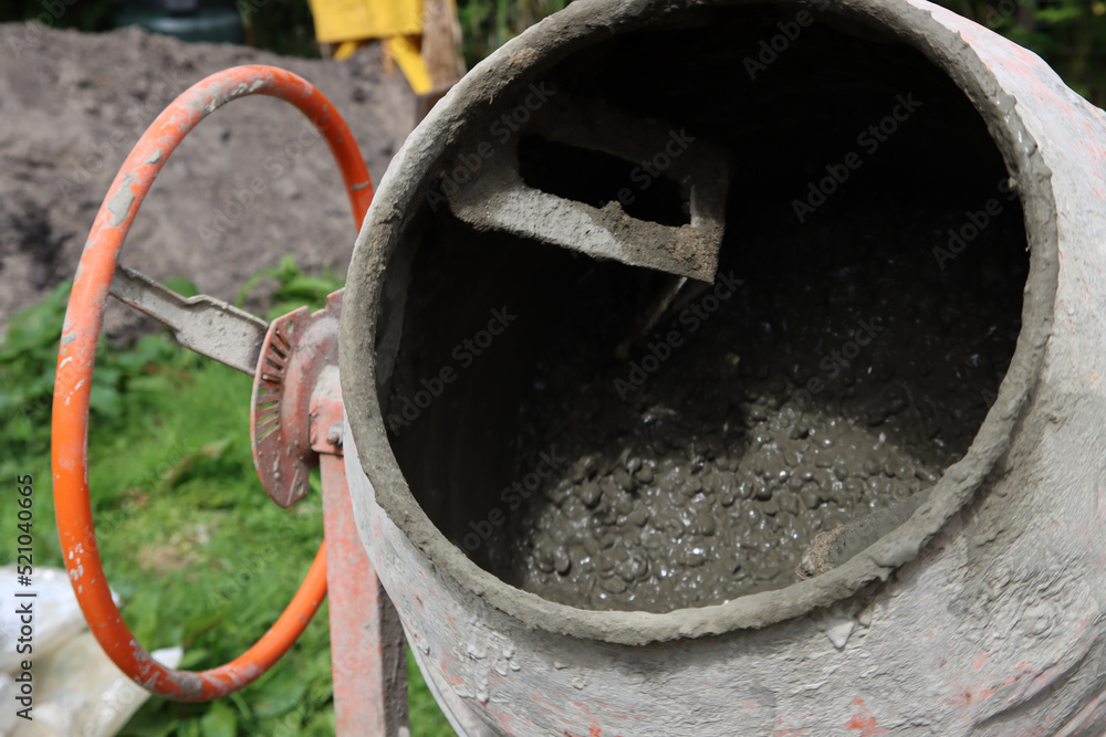 Concrete mixer close up photo. Construction worker equipment. Industrial cement mortar standing outdoors. Concrete mixer close up photo. Construction worker equipment. Industrial cement mortar standing outdoors.