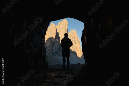 Silhouette of a tourist enjoying the view on the Three Peaks of Lavaredo, (Tre cime di Lavaredo) framed by a cave. The Three Peaks of Lavaredo are the undisputed symbol of the Dolomites, Italy
