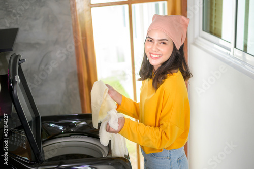 Young happy woman doing laundry using washing machine at home, laundry concept