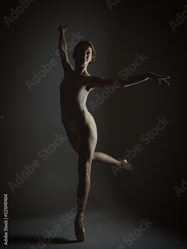 charming ballerina posing in the studio on a dark background