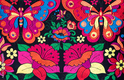 Colorful locally crafted fabric from Chiapas, Mexico.  Flowers edged in various colors and butterflies on a black background