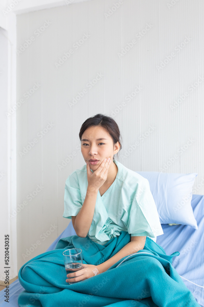 Asian female patient Have a toothache With her right hand held onto the cheek And her face looks sad because of the pain And her left hand held a glass of water. Asian female patient Have a toothache With her right hand held onto the cheek And her face looks sad because of the pain And her left hand held a glass of water.