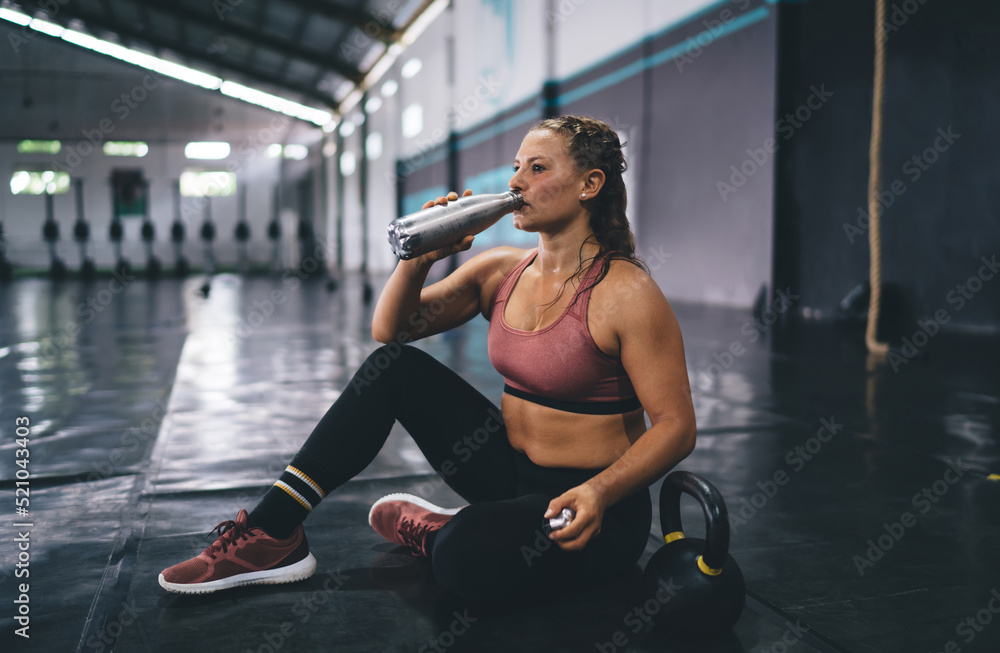 Side view of Caucasian female in activewear drinking water from bottle