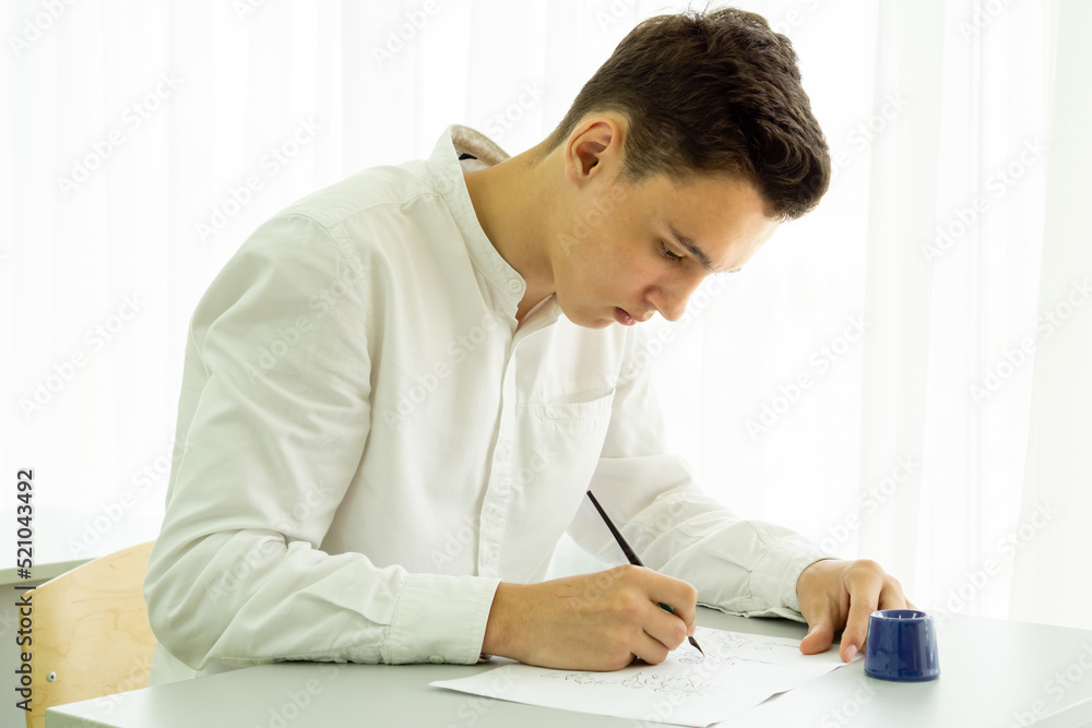A student learns to write with a fountain pen at a white table. Back to school concept, exams, additional education. High quality photo A student learns to write with a fountain pen at a white table. Back to school concept, exams, additional education. High quality photo