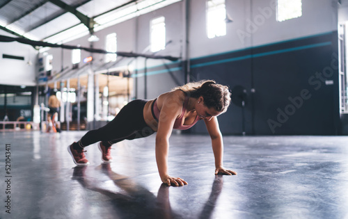 Strong Caucasian woman with muscular body shape doing push ups during morning workout training, motivated female athlete keeping vitality and wellness on intensive activity - crossfit exercising