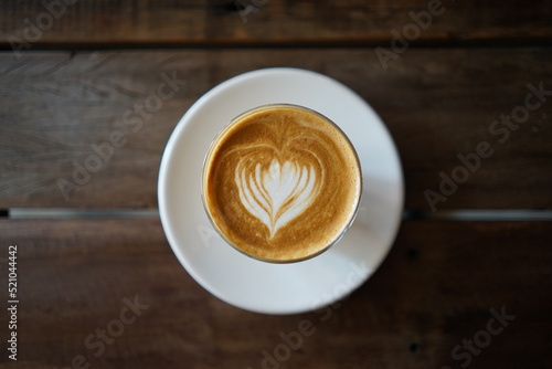 A cup of cafe latter with latte art in white cup with wooden table background
